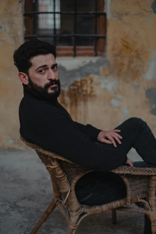 a man with beard sitting on chair looking to the side