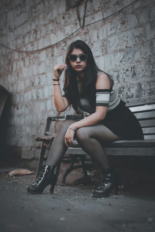 a young woman with black stockings sitting on a bench