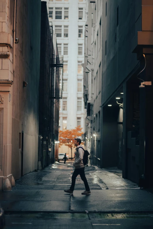 a man walks down an alley way in the rain