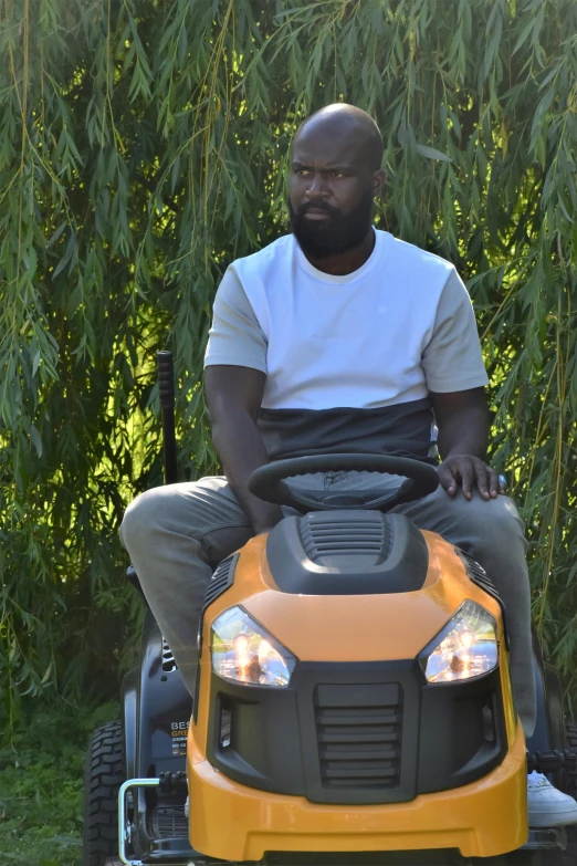 a man sits on top of a yellow vehicle in the grass