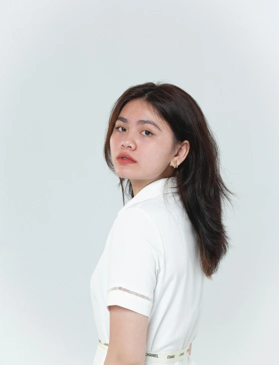 a young woman standing against a white wall