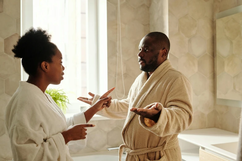 two people are in a bathroom, one is pointing to a plant