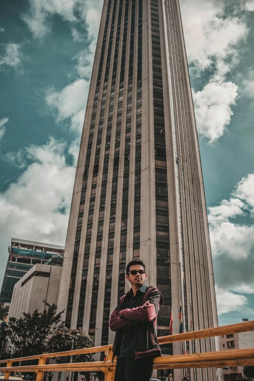 a man poses in front of the tall building