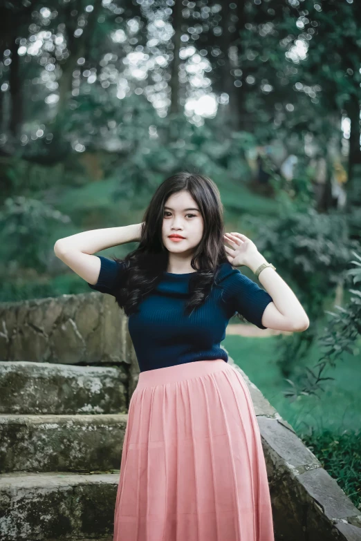 a girl in a blue top and a pink skirt standing on the stairs