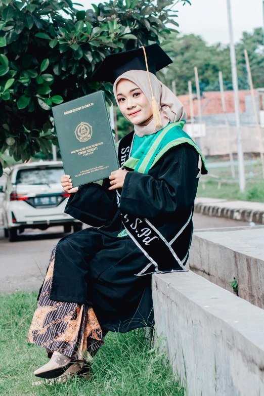 a young woman in black graduation gown holding an open book