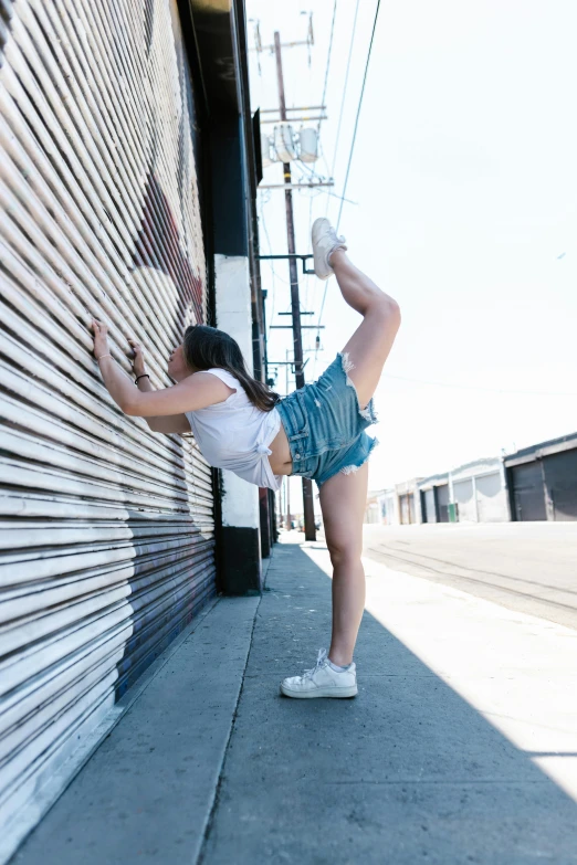 a woman leaning against the wall posing with her legs crossed