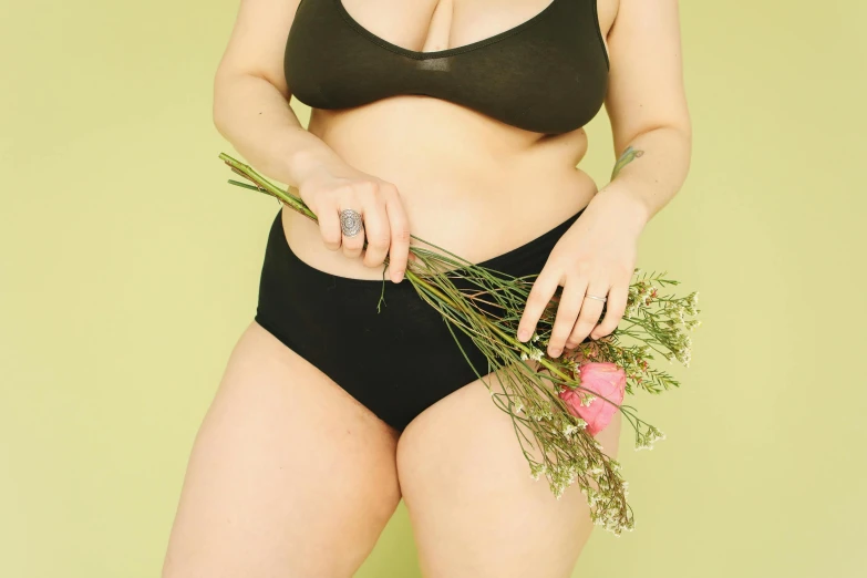 woman in a bikini holding greenery and posing for the camera