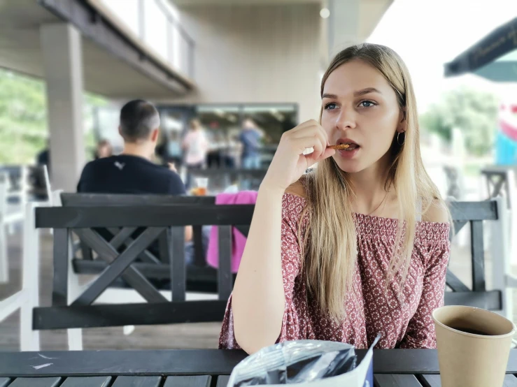 girl at a table holding her mouth open as if she was biting into a piece of food