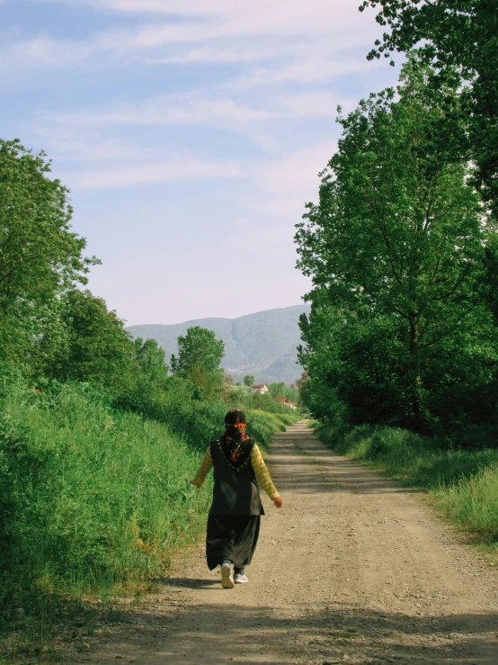 a woman in black dress running down a dirt road