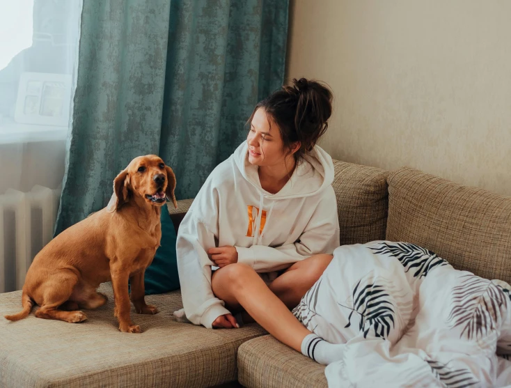 there is a woman sitting on the couch with a dog