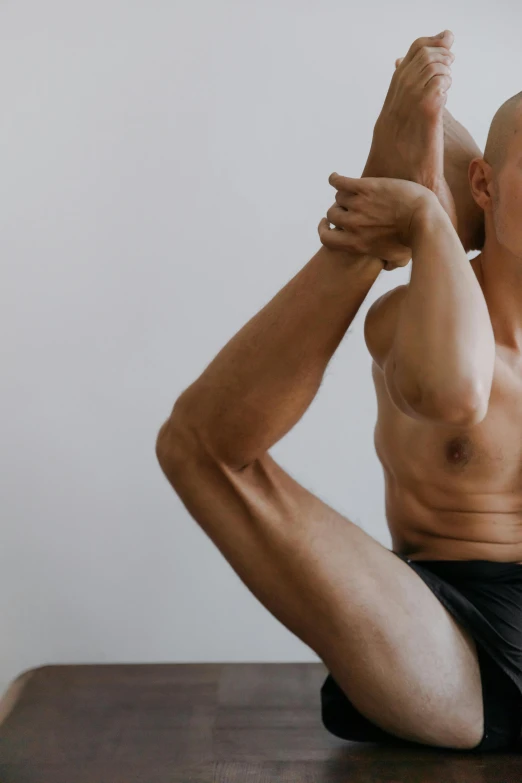 a man is posing in yoga position on a brown wooden table