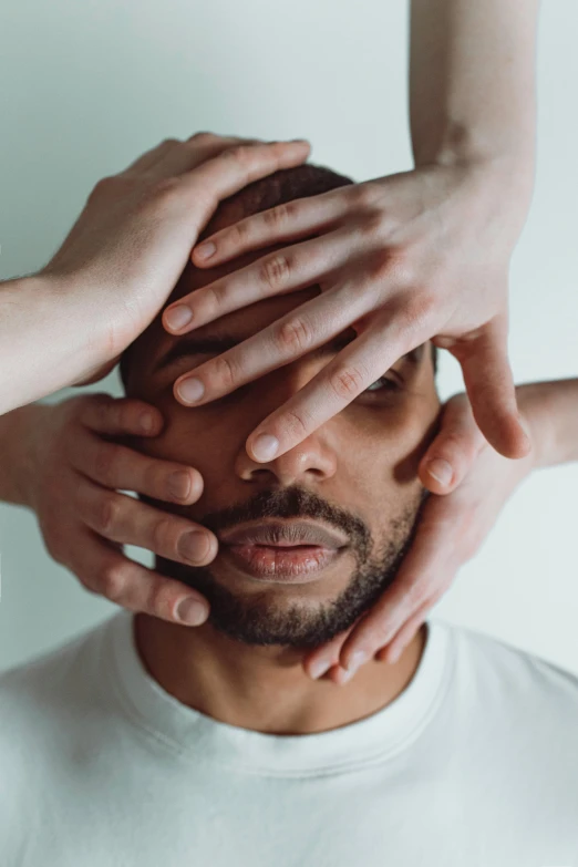 a group of hands on top of the face of a man