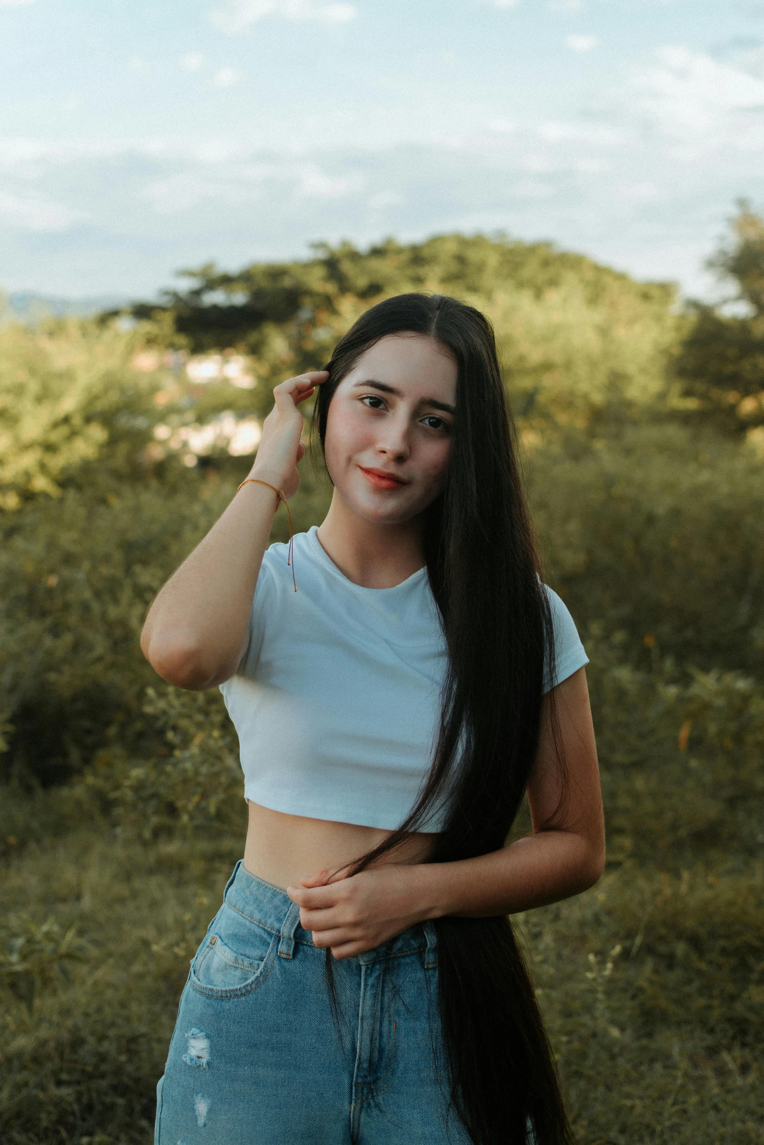 a girl with long hair poses for a po in a field