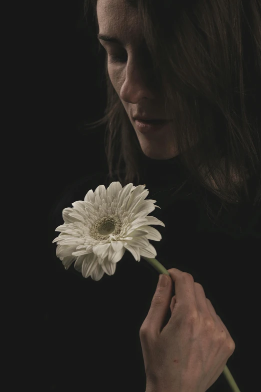 a woman holds a white flower in her right hand