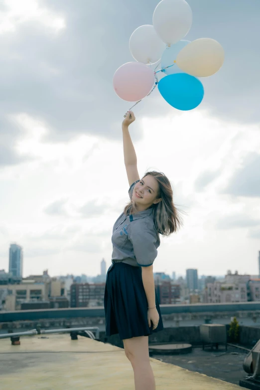 a girl holding many balloons as she poses with her legs crossed