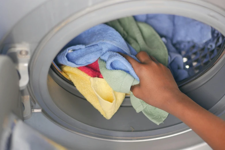 a woman is holding a rag in front of the washing machine