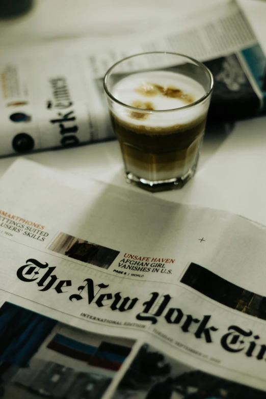 a cup of coffee on the news paper with some food