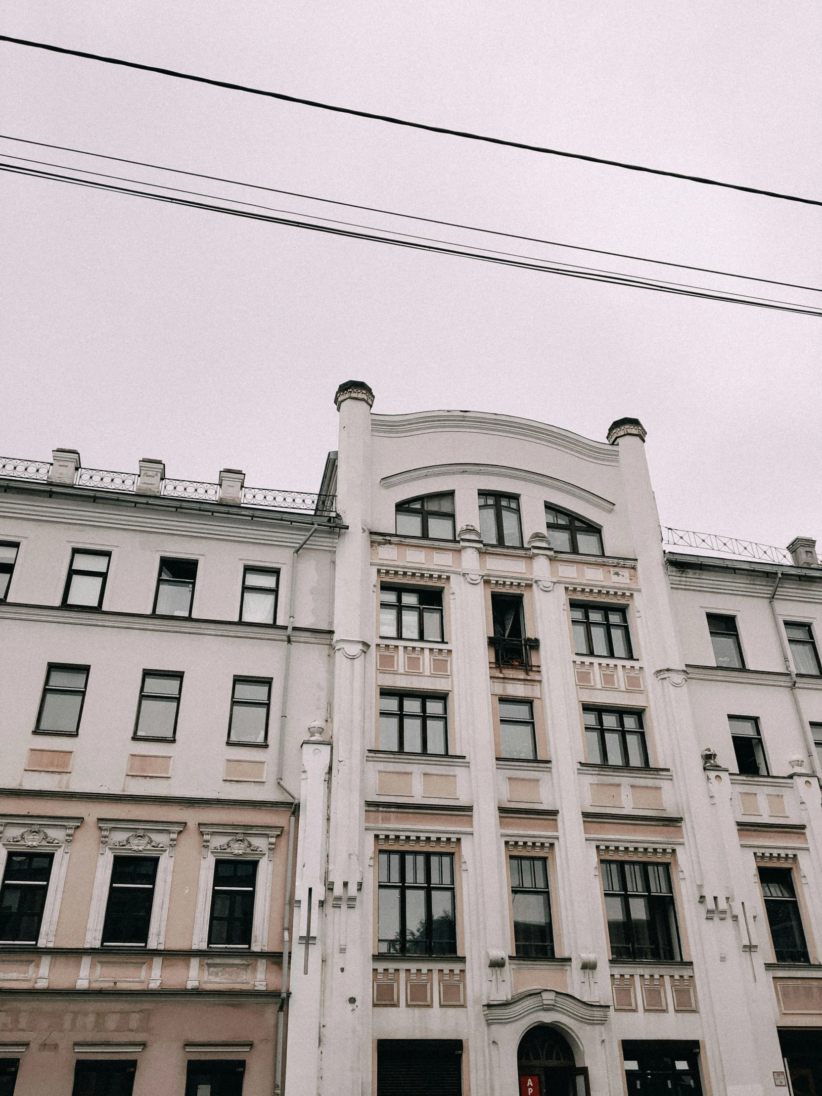 large white building with lots of windows with people walking by