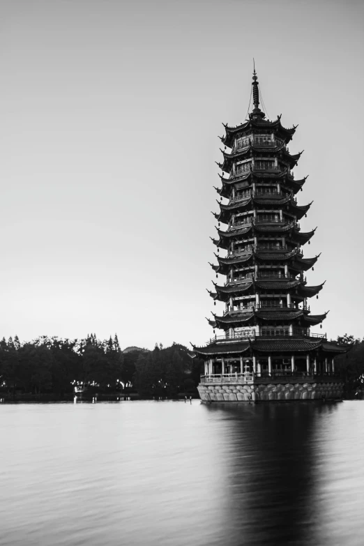 a tall building sitting on top of a lake next to a forest