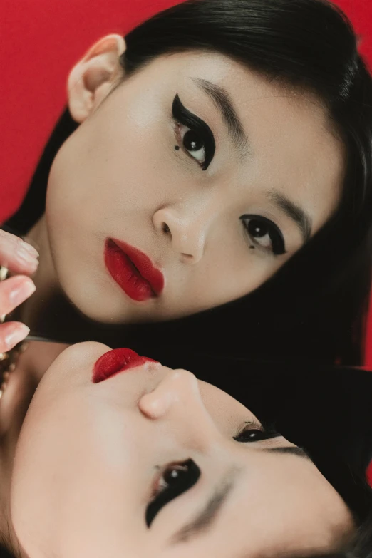 an asian couple with very large black lashes, wearing red and black