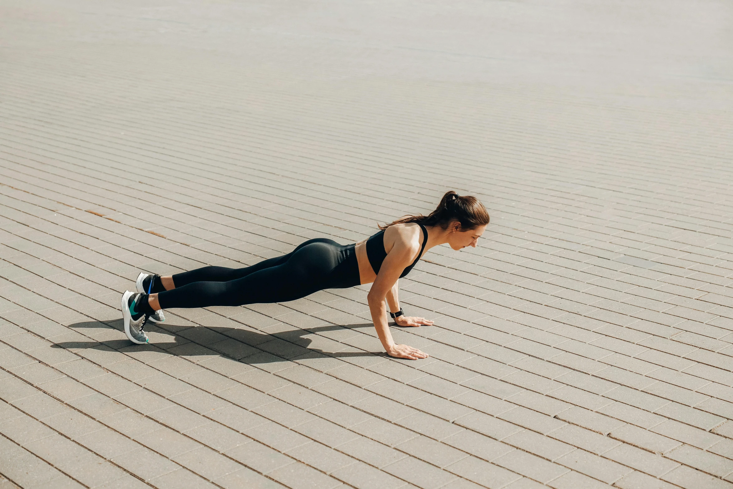 a woman in black top doing h ups on a sand area