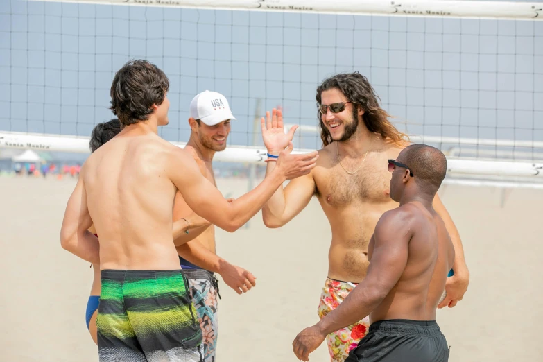 four men standing on a beach and smiling