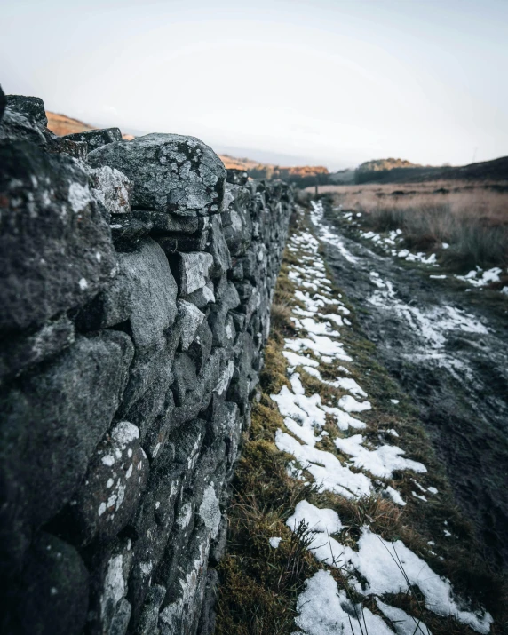 a stone wall with snow on it near the ground