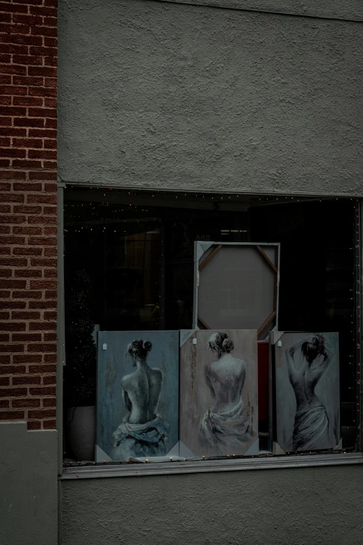 a window display of paintings hanging in the windows