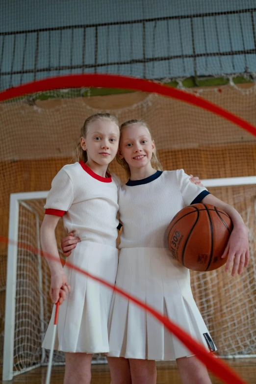 two little girls standing on a court with a basketball