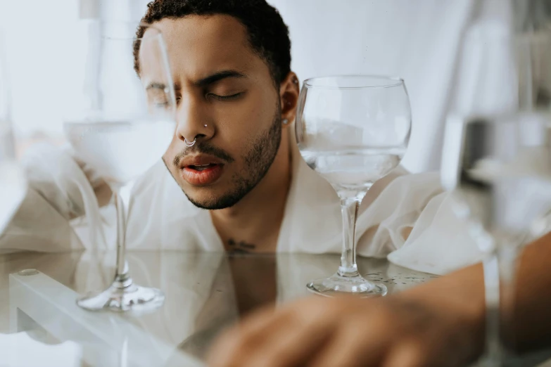 a man standing by a counter with two wine glasses