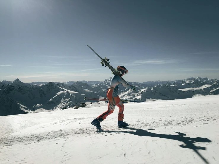 person walking on snow covered ground carrying skis and poles