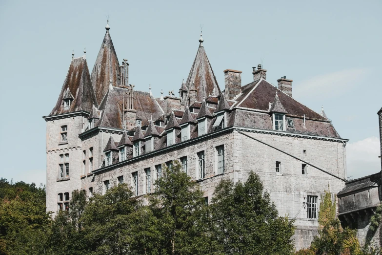 a stone castle with pointed roofs surrounded by trees