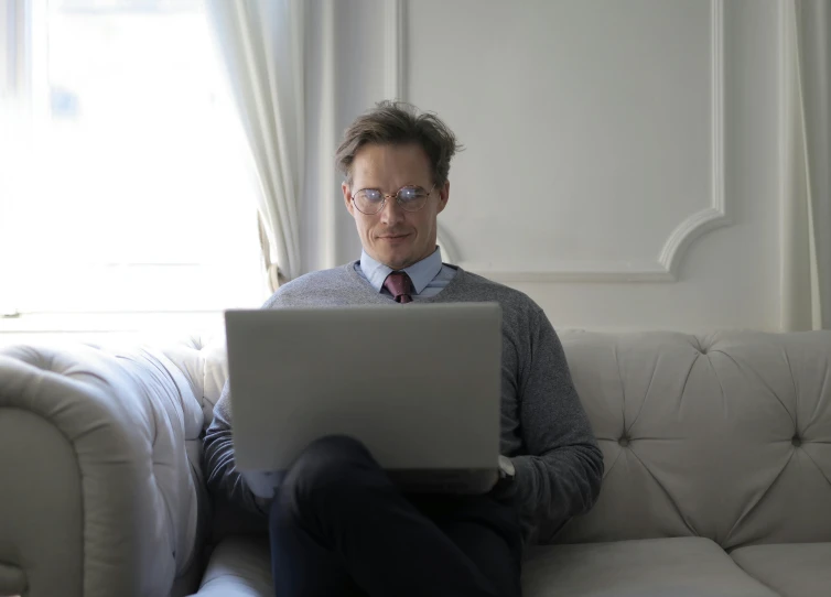 man sitting on a couch with a laptop