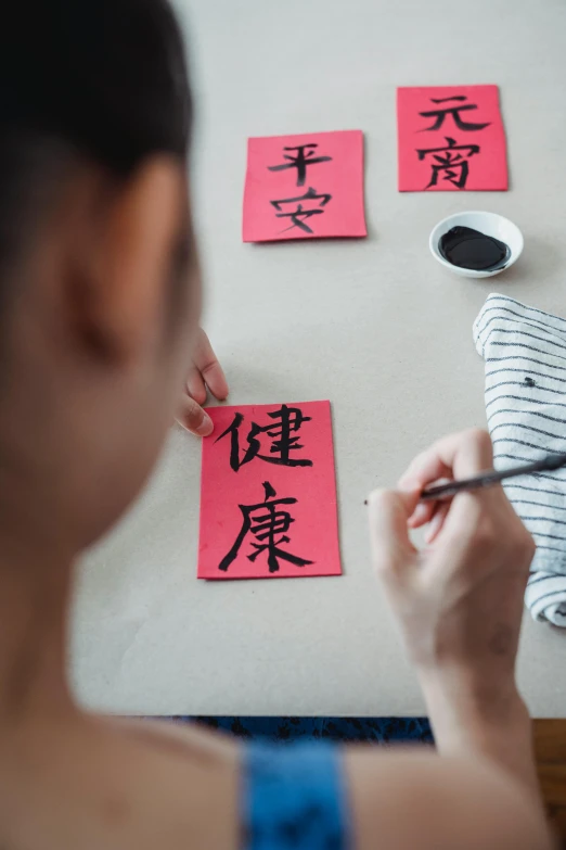 a person writing on an item with chinese calligraphy