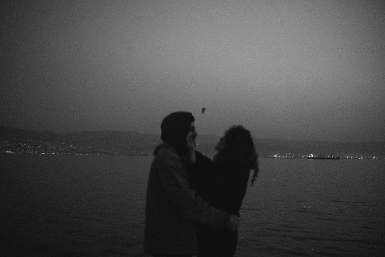 two people flying an umbrella near the ocean at night