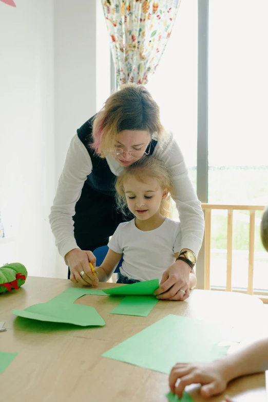 the woman is helping the child do crafts on the table