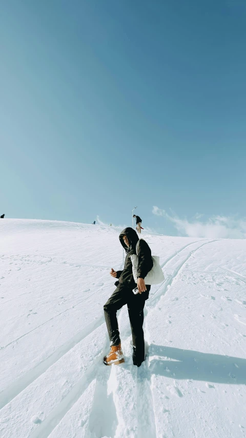 two snow boarders, one carrying the board, standing in snow