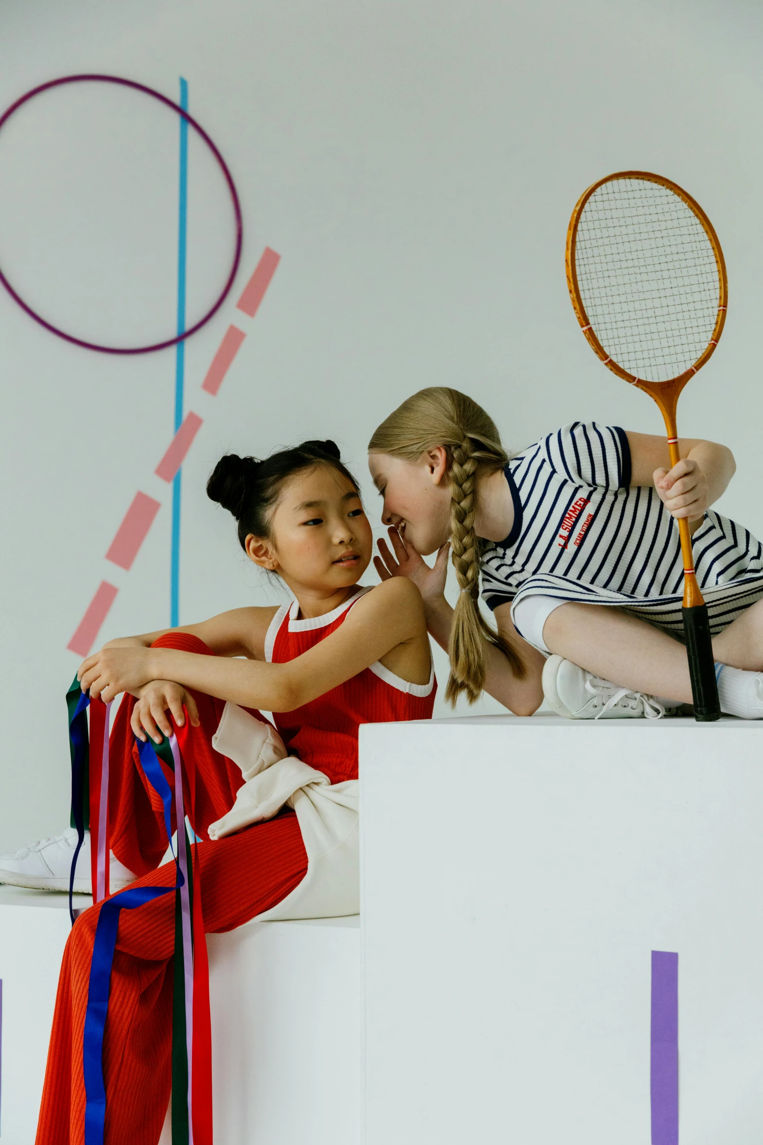 two s in sports uniforms are sitting on a pedestal