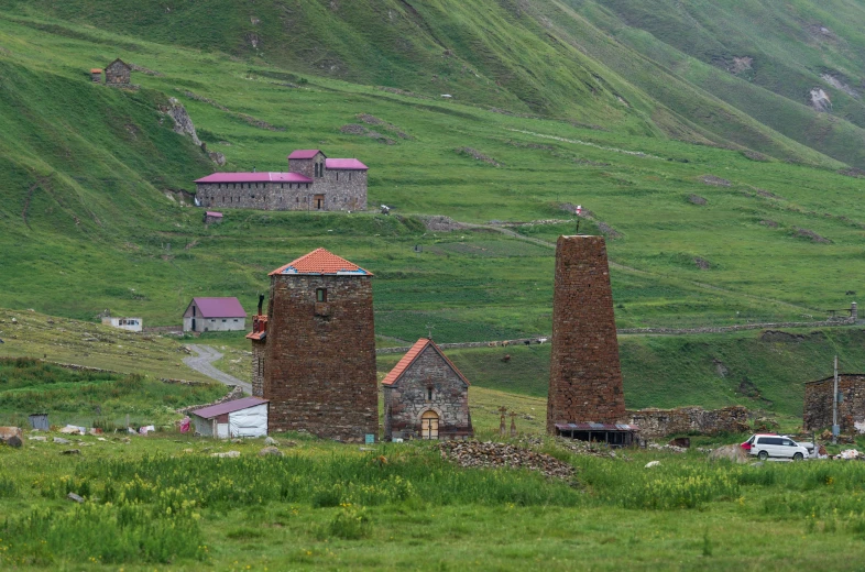 a group of farm buildings sitting on top of a green hillside