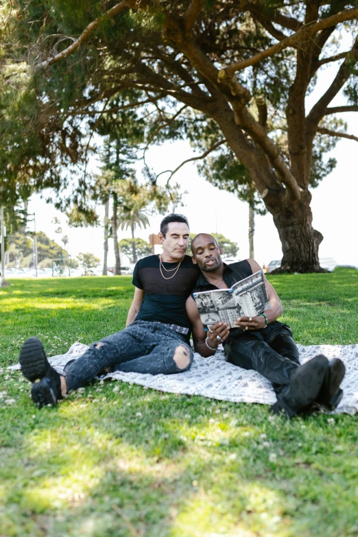 two people are posing on a blanket under a tree