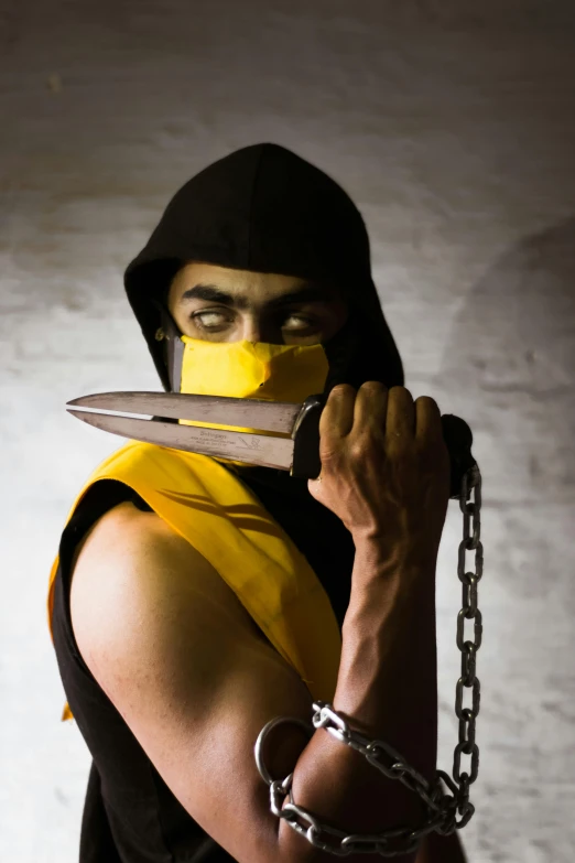 a man in black and yellow outfit holding a pair of knives