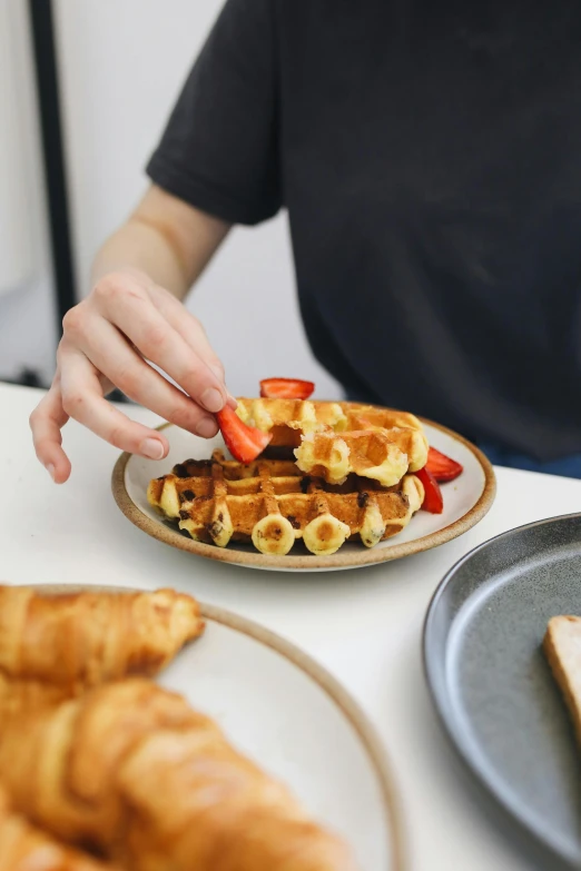 a woman is touching a waffle with fruit on top