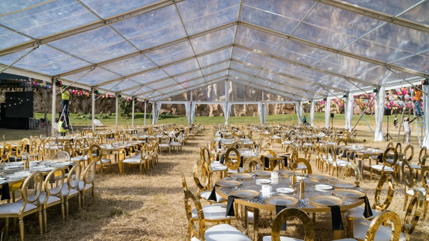 an outdoor function tent filled with lots of tables and chairs