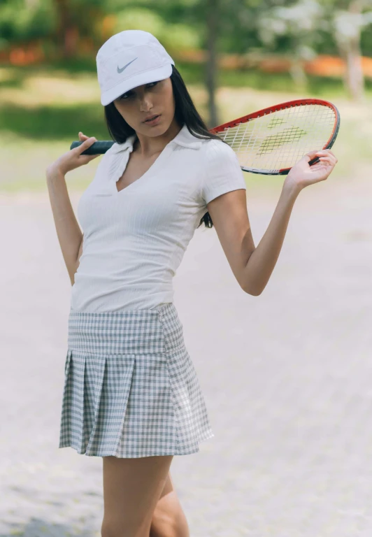 young woman wearing short dress holding tennis racket