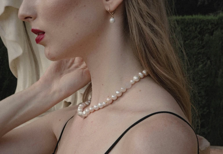 the back of a woman's head wearing a pearled necklace