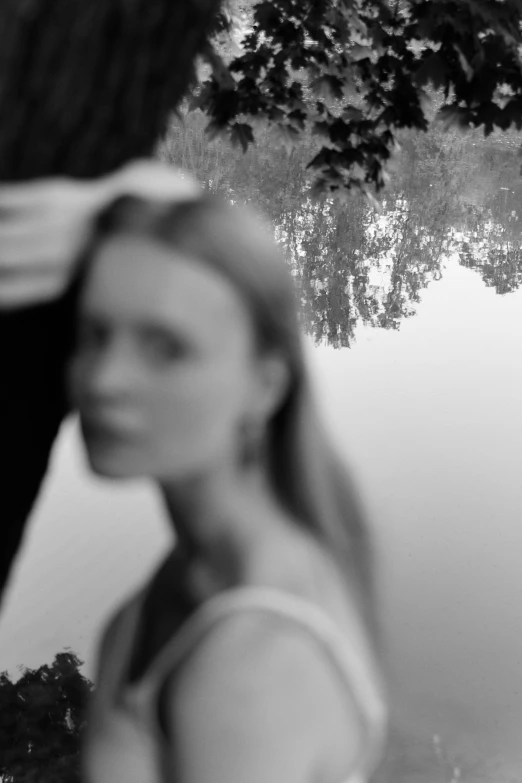 a couple with the tree reflected in a small pond