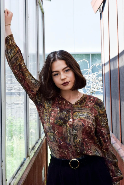 young woman standing by window looking straight ahead