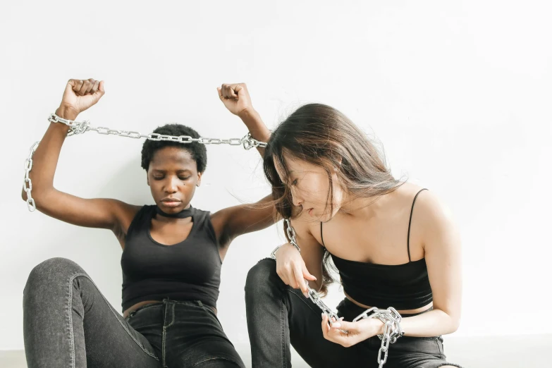 two people sitting on the floor attached to chains