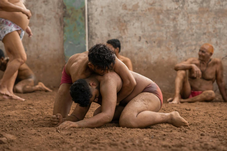 the men are in the sand wrestling