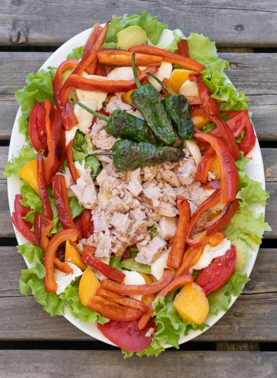 a salad with chicken, tomatoes, lettuce and other toppings on it